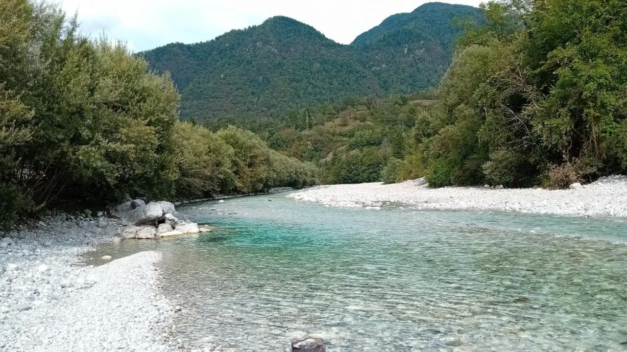 Reka s prodom, za njo gozdnata pobočja