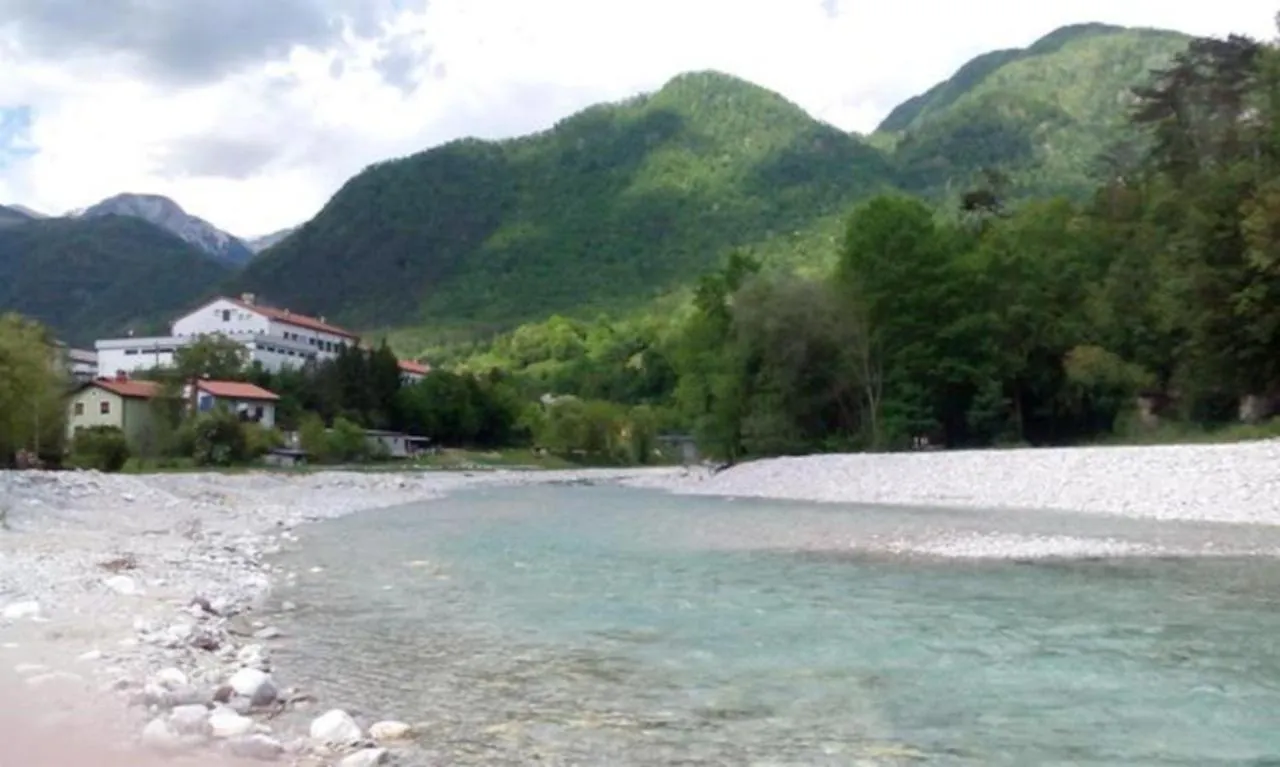 Prodnata struga reke v Tolminu, za njo hiše in gore
